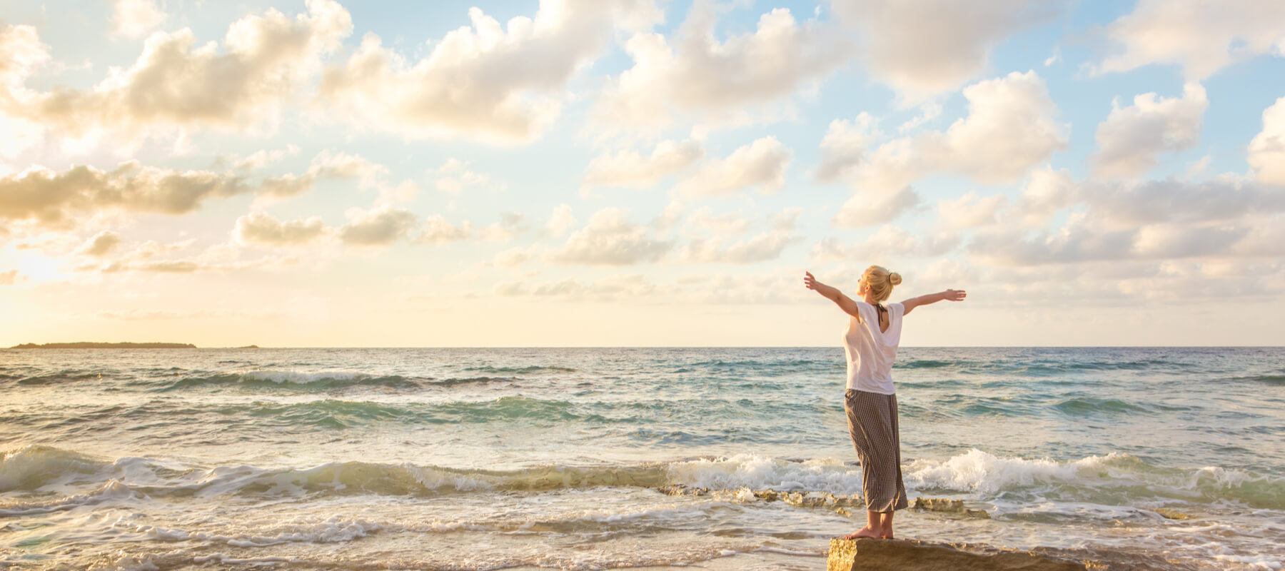 Frau am Meer, arme weit zum himmel, blick aufs wasser